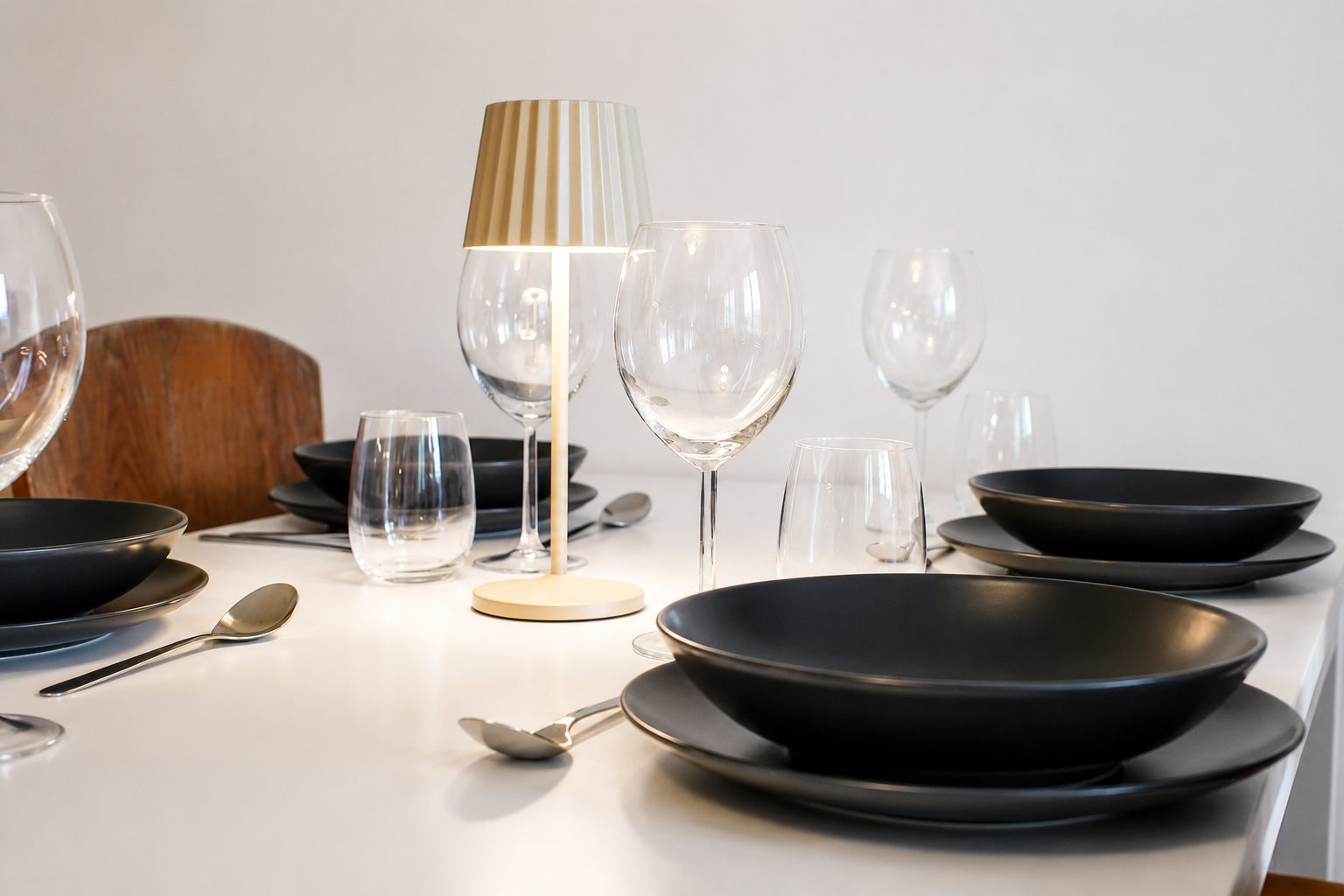 Gedeckter Tisch mit Weingläsern und dunklem Geschirr
